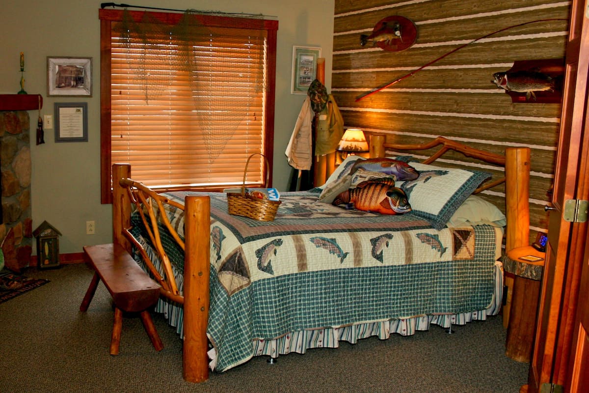 A cozy bedroom with a wooden bed, a bench, and a window with blinds.