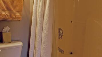 A bathroom with a toilet, a shower curtain, and a bathtub.