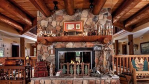 A stone fireplace with a wooden mantel, surrounded by rustic decor and a wooden ceiling.