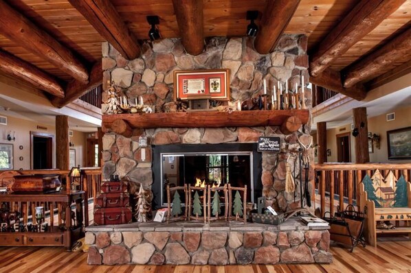 Una chimenea de piedra con repisa de madera, rodeada de decoración rústica y techo de madera.