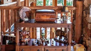 A rustic wooden interior with a wooden bench displaying various animal carvings and a stone wall.