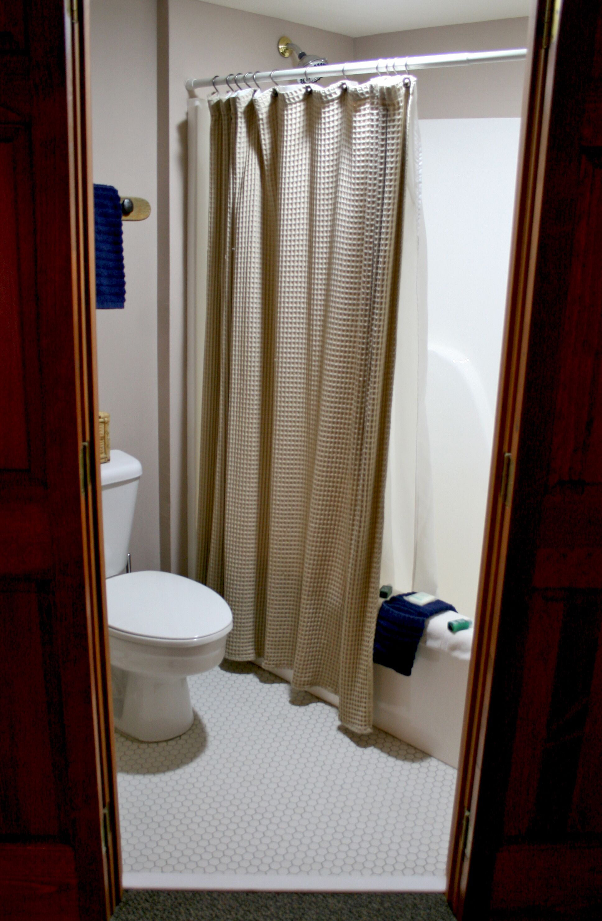 A bathroom with a toilet, a shower curtain, and a towel rack.