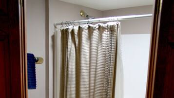A bathroom with a toilet, a shower curtain, and a towel rack.