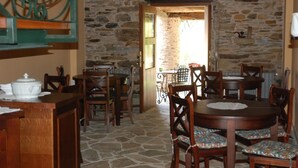 Comedor rústico con paredes de piedra, muebles de madera y un letrero que indica la salida.