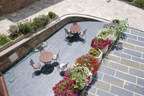 An outdoor patio with stone flooring, surrounded by flower planters and stone walls. - La Casona de Amaido (San Tirso de Abres)