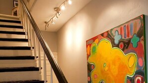 A staircase with black and white steps, a white balustrade, and a colorful abstract painting on the wall. - The Muse Gallery Guesthouse (Milwaukee)