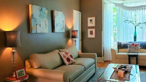 A living room with a sofa, a coffee table, and artwork on the walls. - The Muse Gallery Guesthouse (Milwaukee)