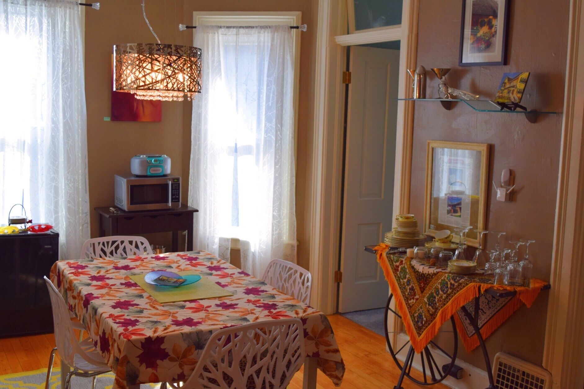 A dining area with a table set for two, a microwave, and a decorative lamp.