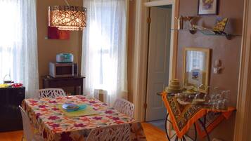 A dining area with a table set for two, a microwave, and a decorative lamp.