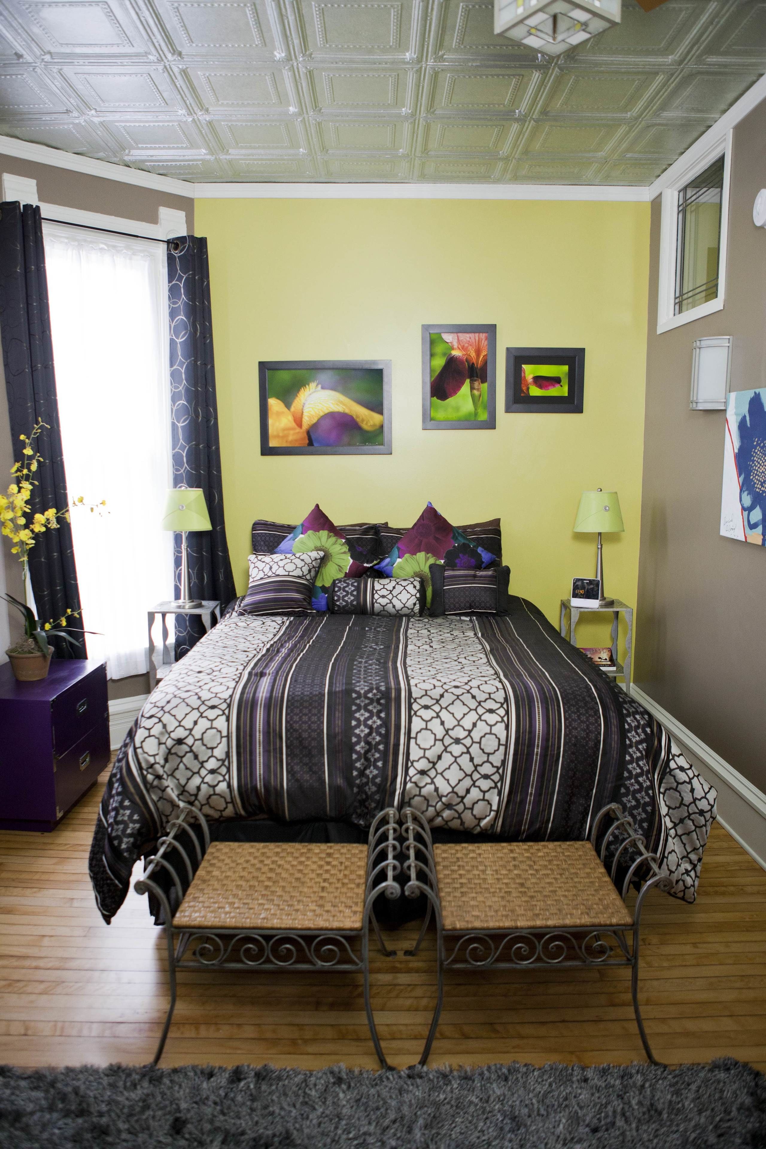 Une chambre à coucher avec un lit, une petite table, une lampe et une plante en pot.