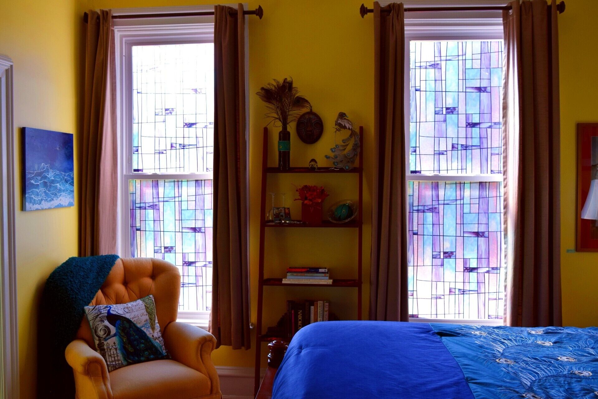 Una habitació amb un llit, una cadira, una estanteria i una finestra amb cortines.
