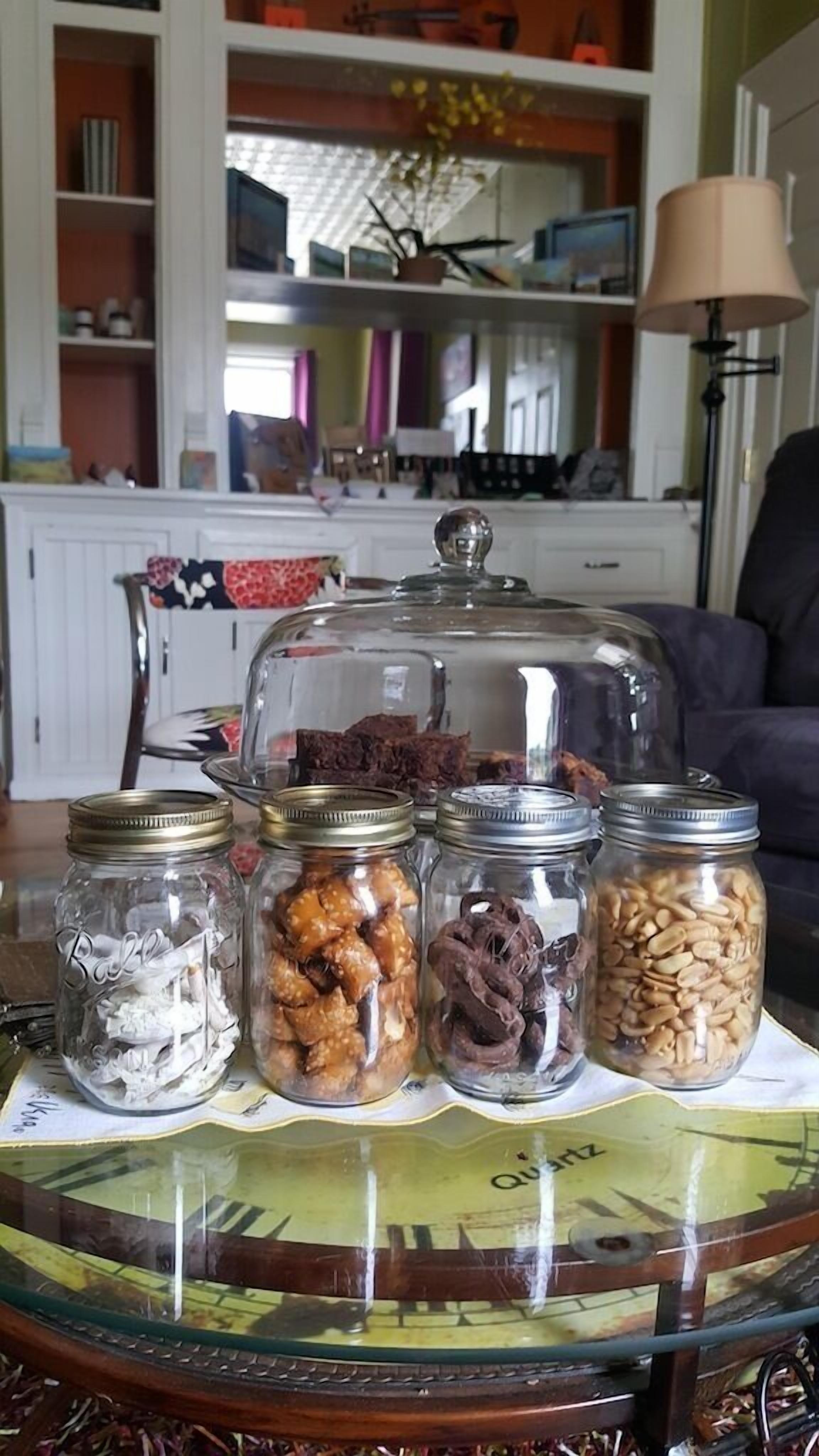 A table with four glass jars containing various food items, a glass dome cover, and a tablecloth with a map design.