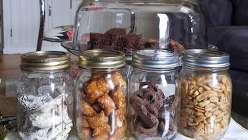 A table with four glass jars containing various food items, a glass dome cover, and a tablecloth with a map design.