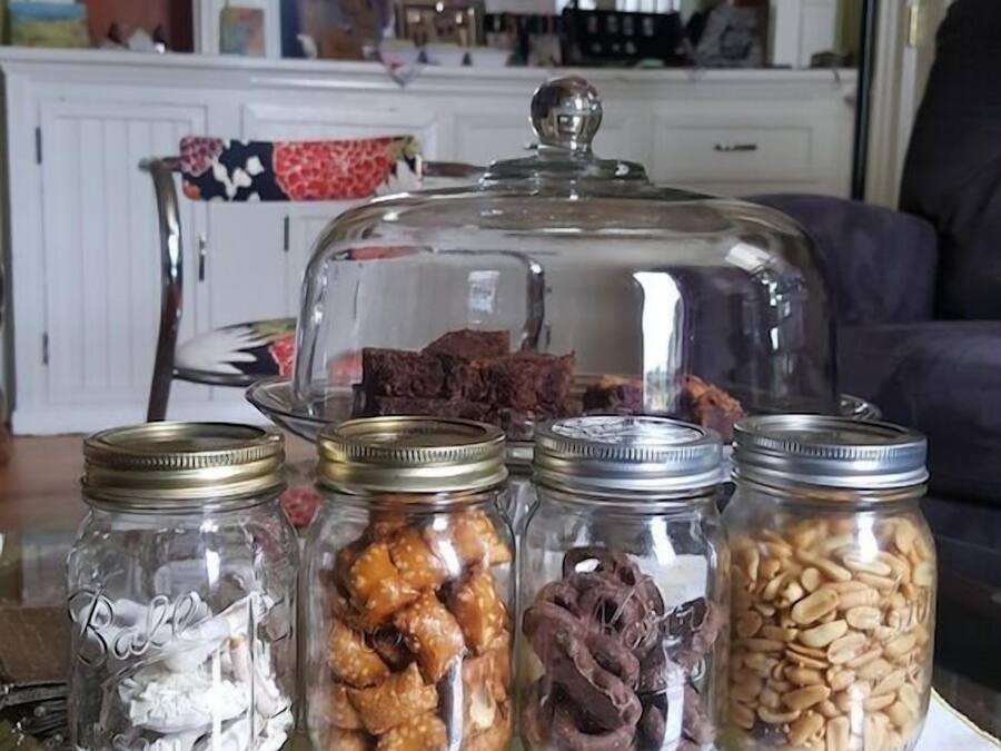 A table with four glass jars containing various food items, a glass dome cover, and a tablecloth with a map design.