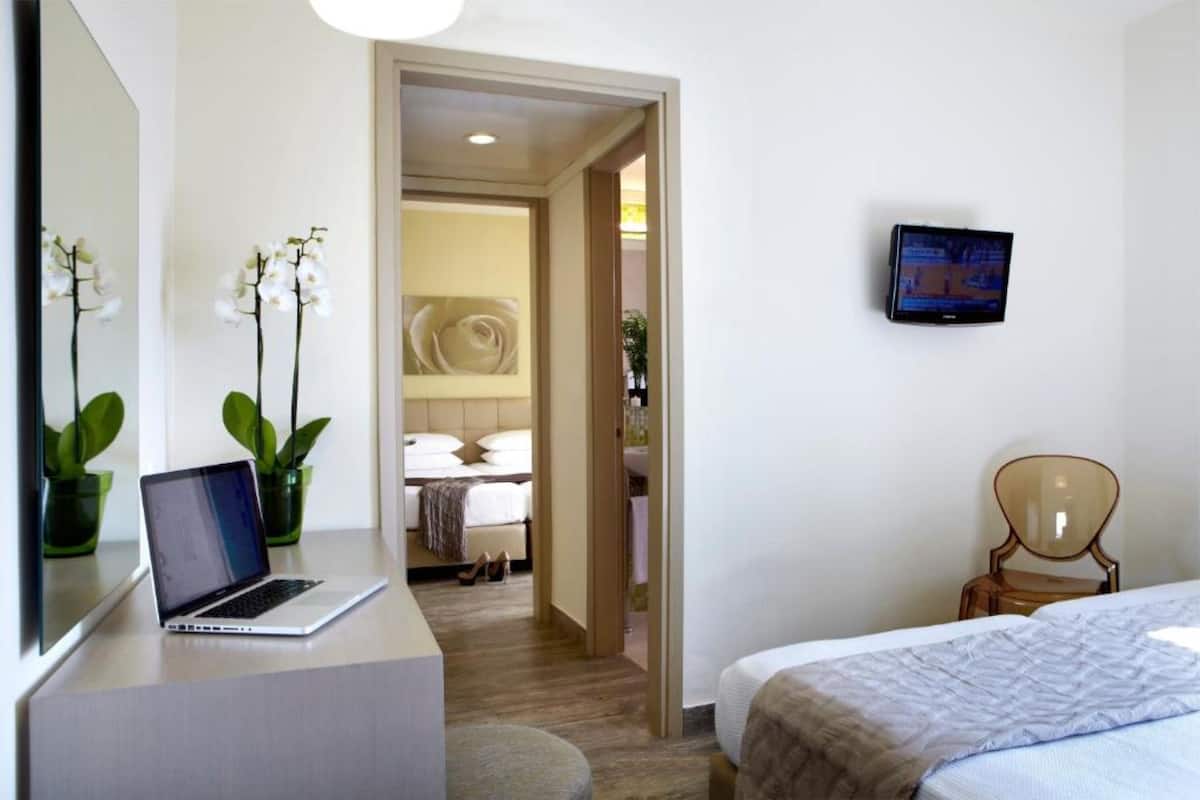 Een hotelkamer met een bed, een bureau met een laptop, een televisie en een stoel.