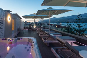 Terraza en la azotea con sillones de descanso, sombrillas y un jacuzzi.