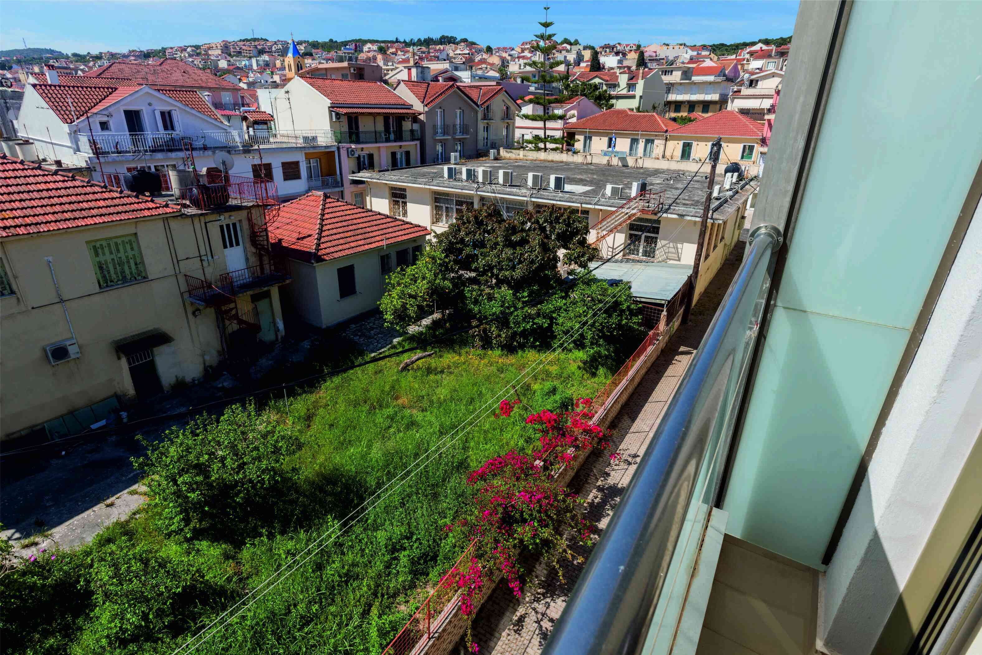 A residential area with red-tiled roofs, balconies, and a view of a town.