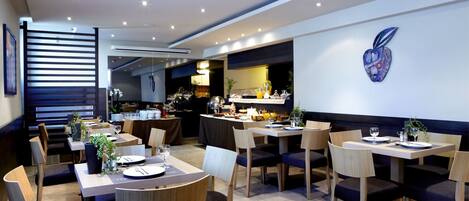 Een modern restaurant met verschillende eetgedeeltes, waaronder een buffet en een bar.