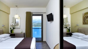 Habitación de hotel con dos camas, televisor, balcón con vistas y un espejo.