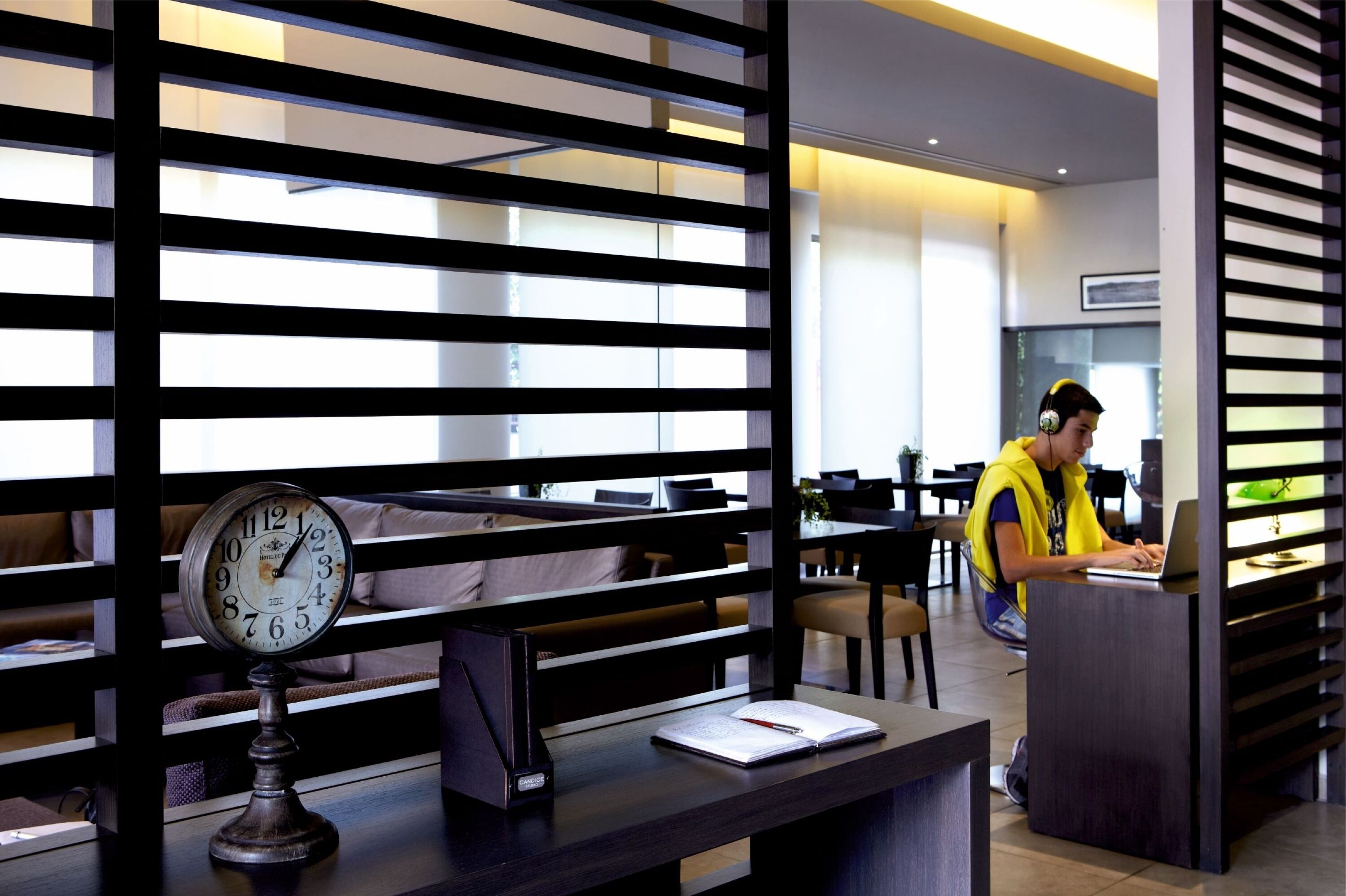 A modern hotel lobby with a reception desk, seating area, and a clock.