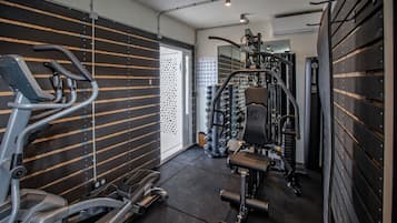 A gym with exercise equipment, a mirrored wall, and a door leading to another room.