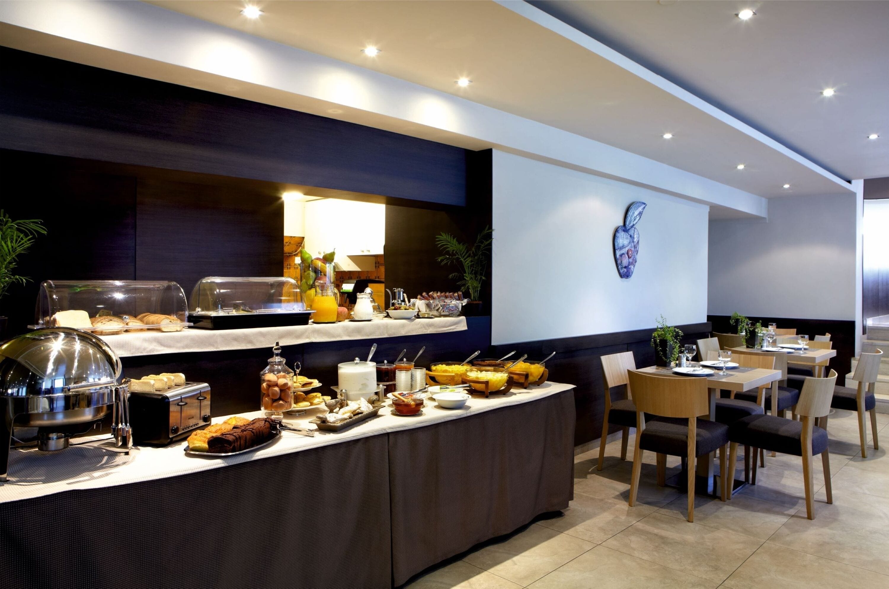 A buffet setup with various food items and a seating area with tables and chairs.