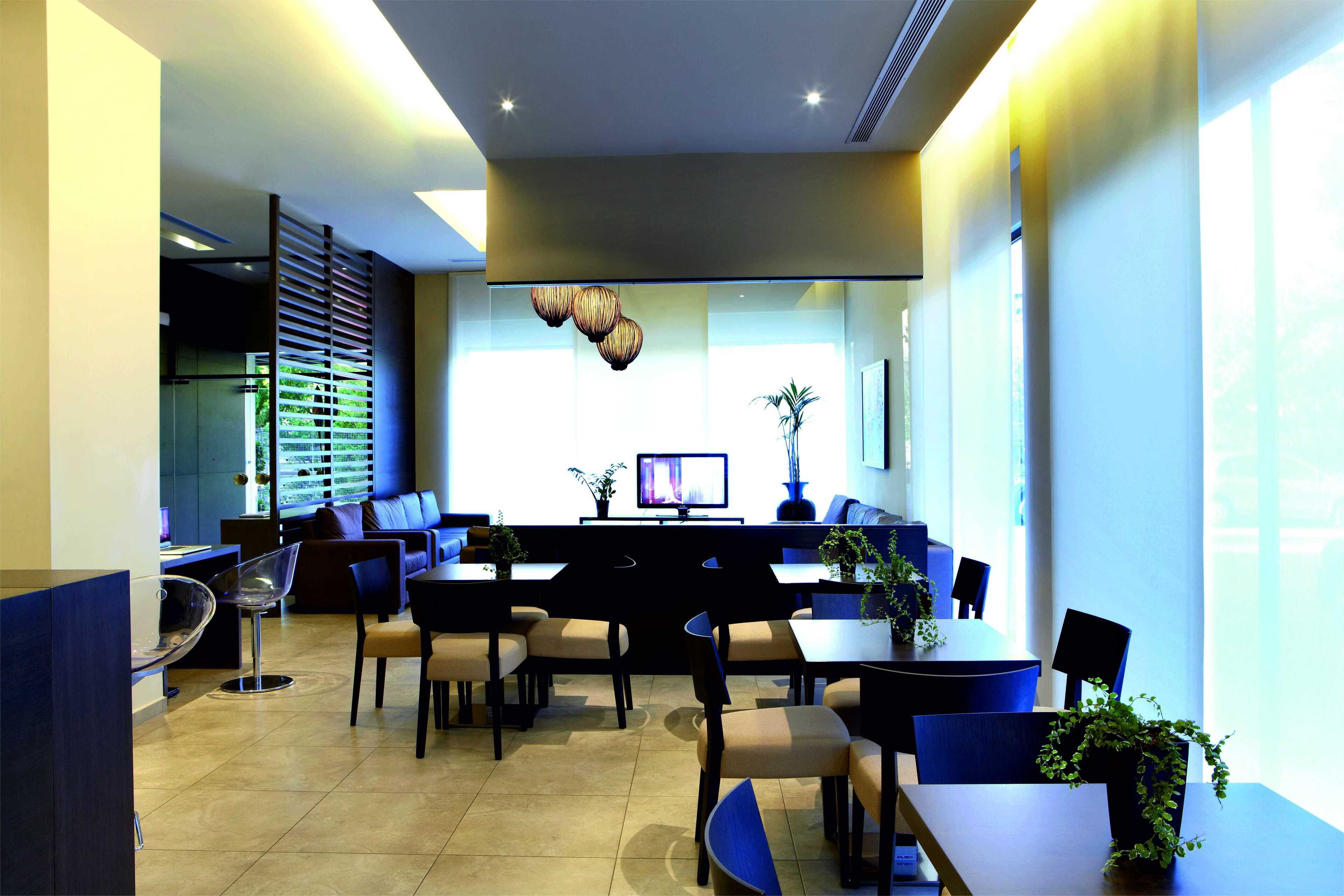 A modern hotel lobby with a reception desk, seating area, and large windows.