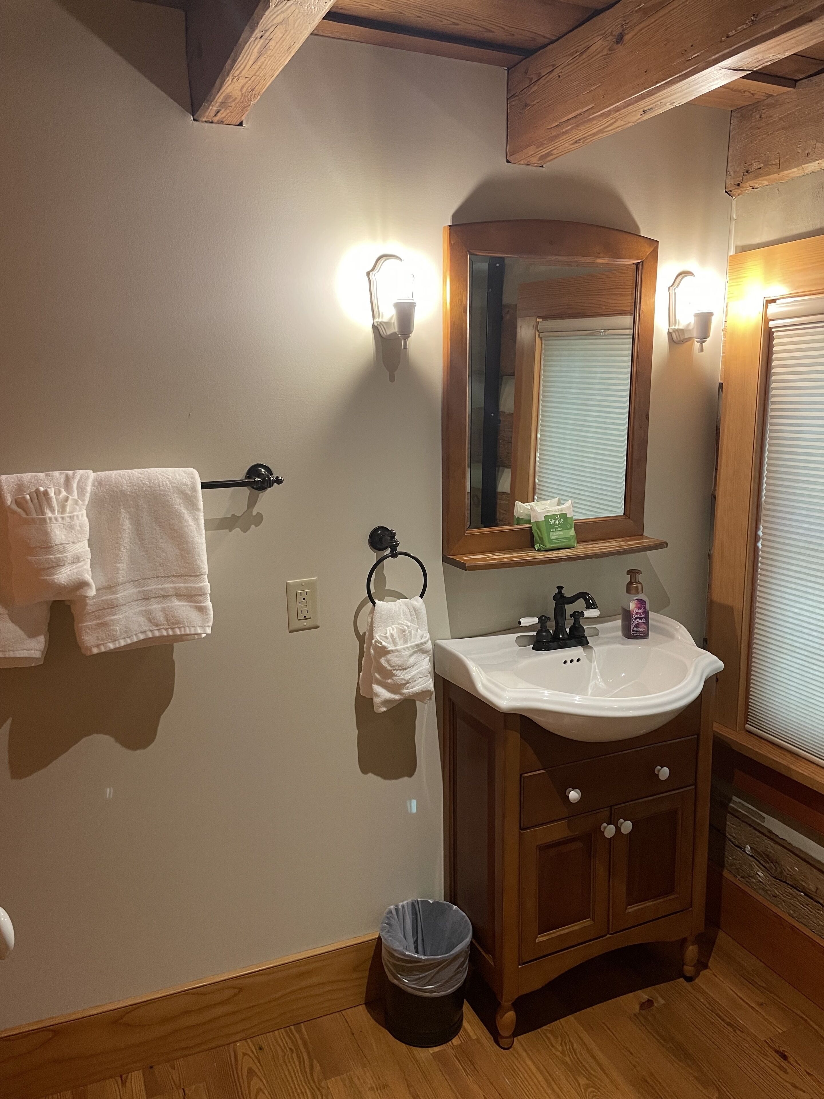 A bathroom with a wooden vanity, a mirror, a sink, and a towel rack.