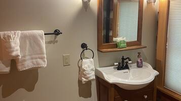 A bathroom with a wooden vanity, a mirror, a sink, and a towel rack.