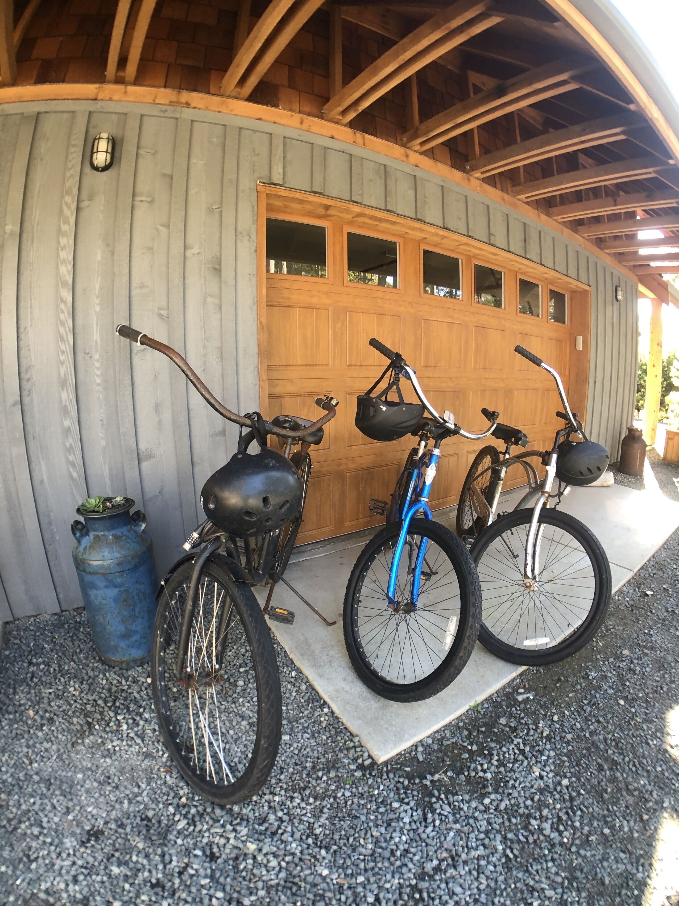 Un espace de stationnement pour vélos abrité, où se trouvent deux vélos, un bleu et un noir, ainsi qu’une bouteille de gaz bleue.