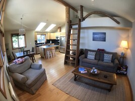 A spacious living area with a sofa, coffee table, and a kitchen in the background.