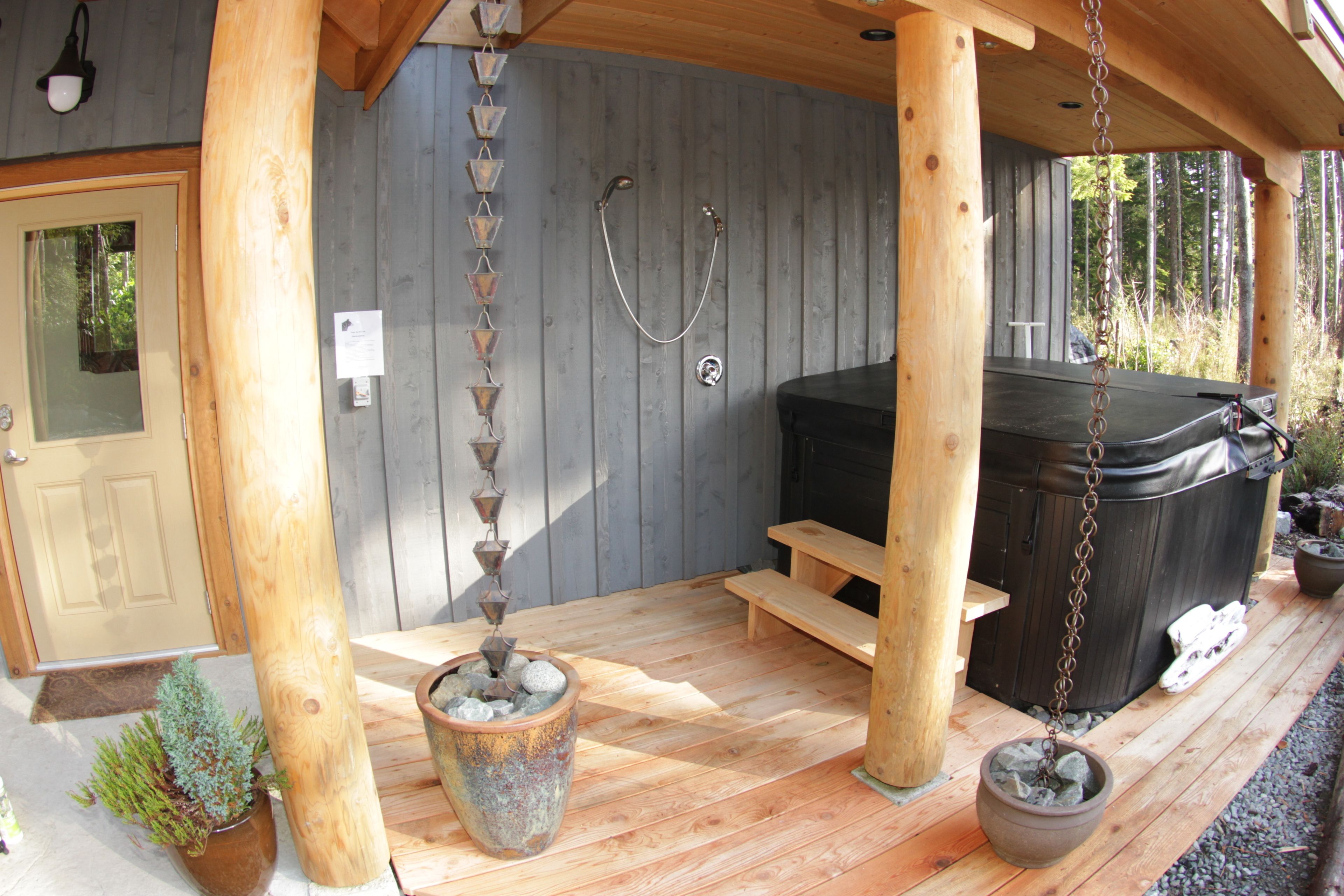 Una terraza de madera con un jacuzzi, un banco de madera y una planta en maceta.