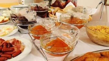 A breakfast buffet with various dishes including pastries, meats, and a variety of spreads.