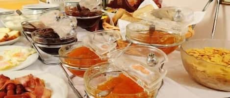 A breakfast buffet with various dishes including pastries, meats, and a variety of spreads.