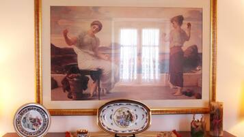 Un quadro incorniciato raffigura due donne, un piatto decorativo e un vaso su un tavolo di legno.