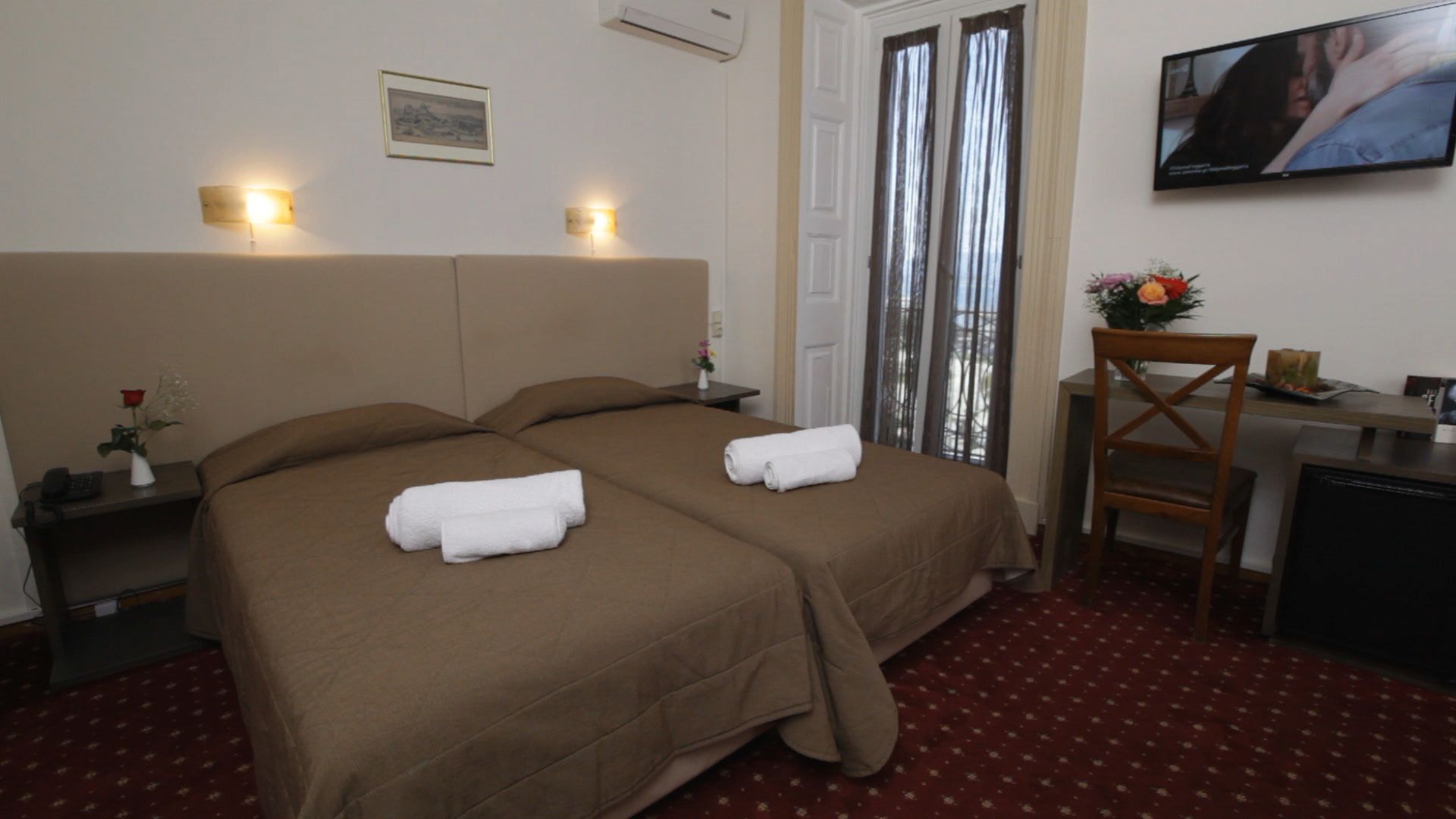 A hotel room with two beds, a TV, a desk, and a chair.