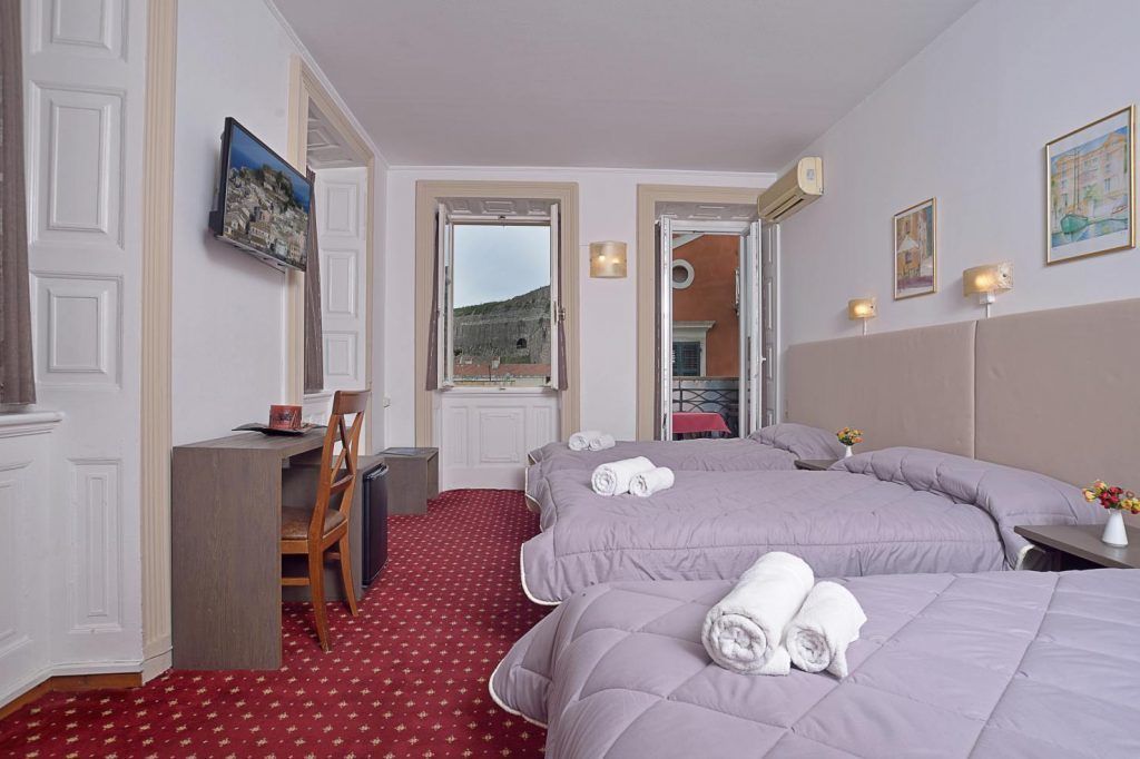 A hotel room with two beds, a desk, a chair, and a TV.