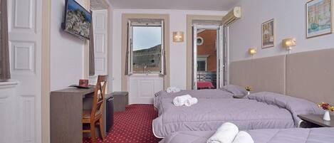 A hotel room with two beds, a desk, a chair, and a TV.