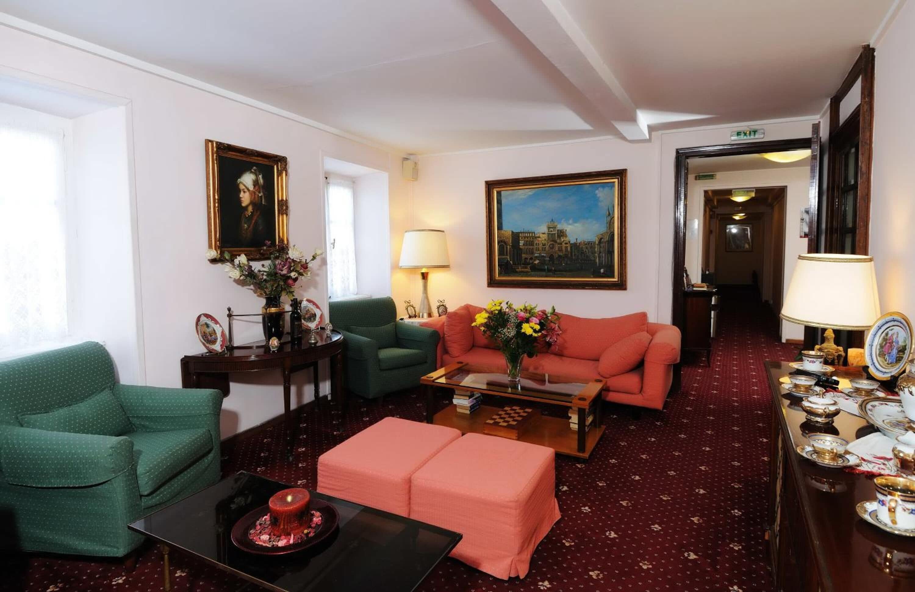 A living room with a green sofa, a red sofa, a coffee table, and a dining table with dishes.