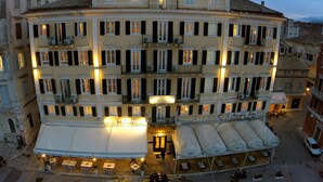 A multi-story hotel with balconies, a ground-level cafe, and outdoor seating. - Konstantinoupolis Hotel - Adults friendly (Corfu)