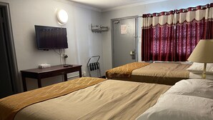 A hotel room with two beds, a TV, a desk, a chair, a door, and a window with curtains.