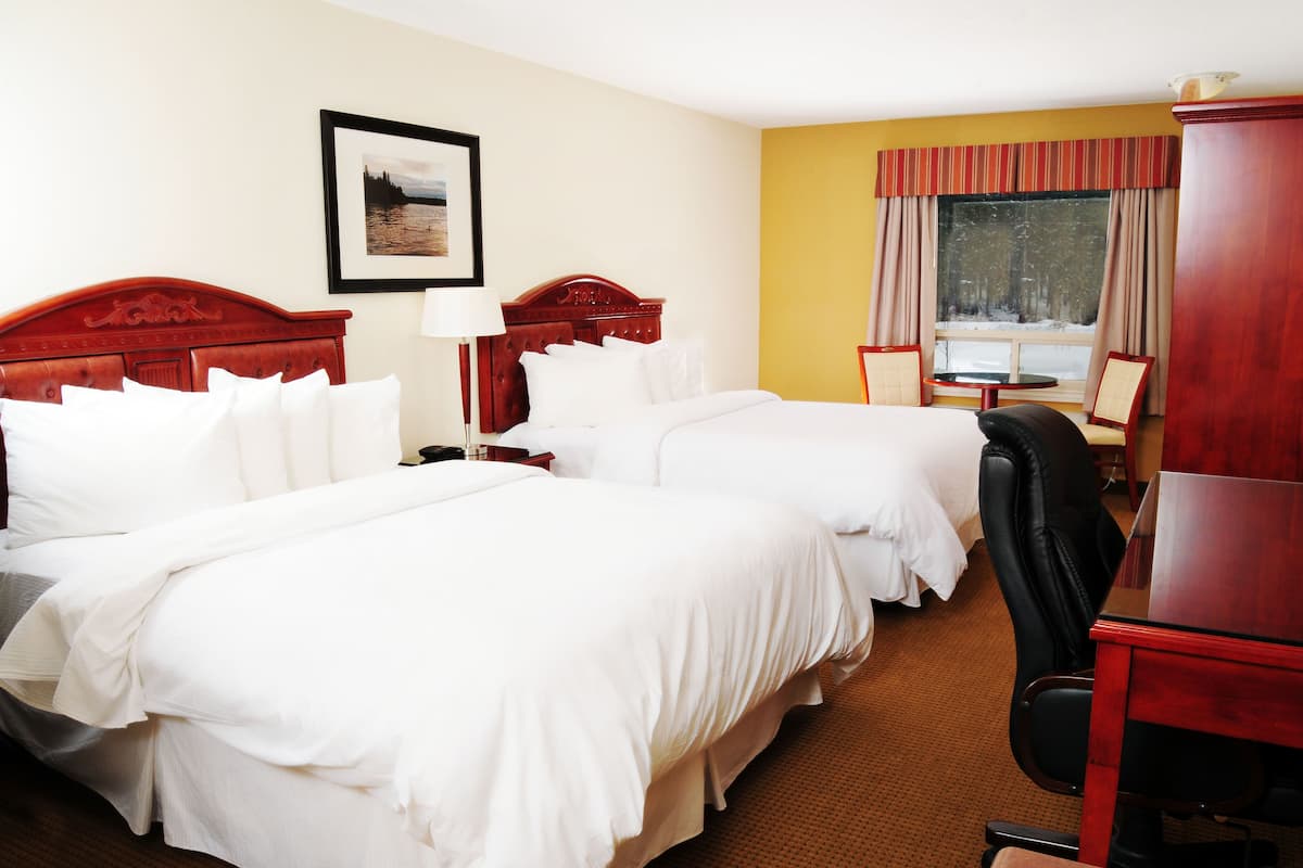 Une chambre d’hôtel avec deux lits, un bureau et une chaise.