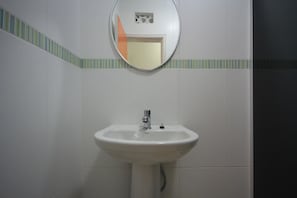 Casa de banho com uma pia branca, um espelho e uma moldura de azulejos listrada.