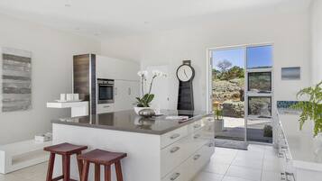 A modern kitchen with a large island, bar stools, and a view of the outdoors.