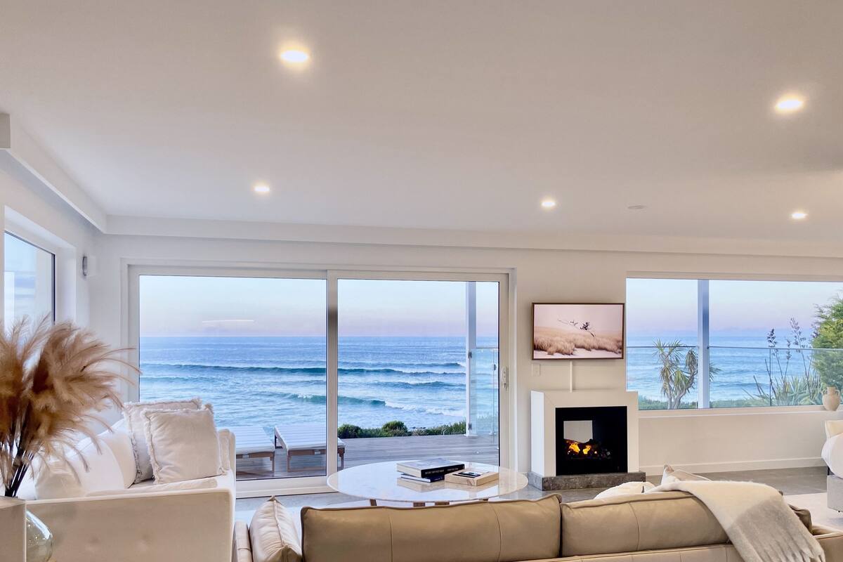 A modern living room with a large ocean view, a fireplace, and a cozy seating area.