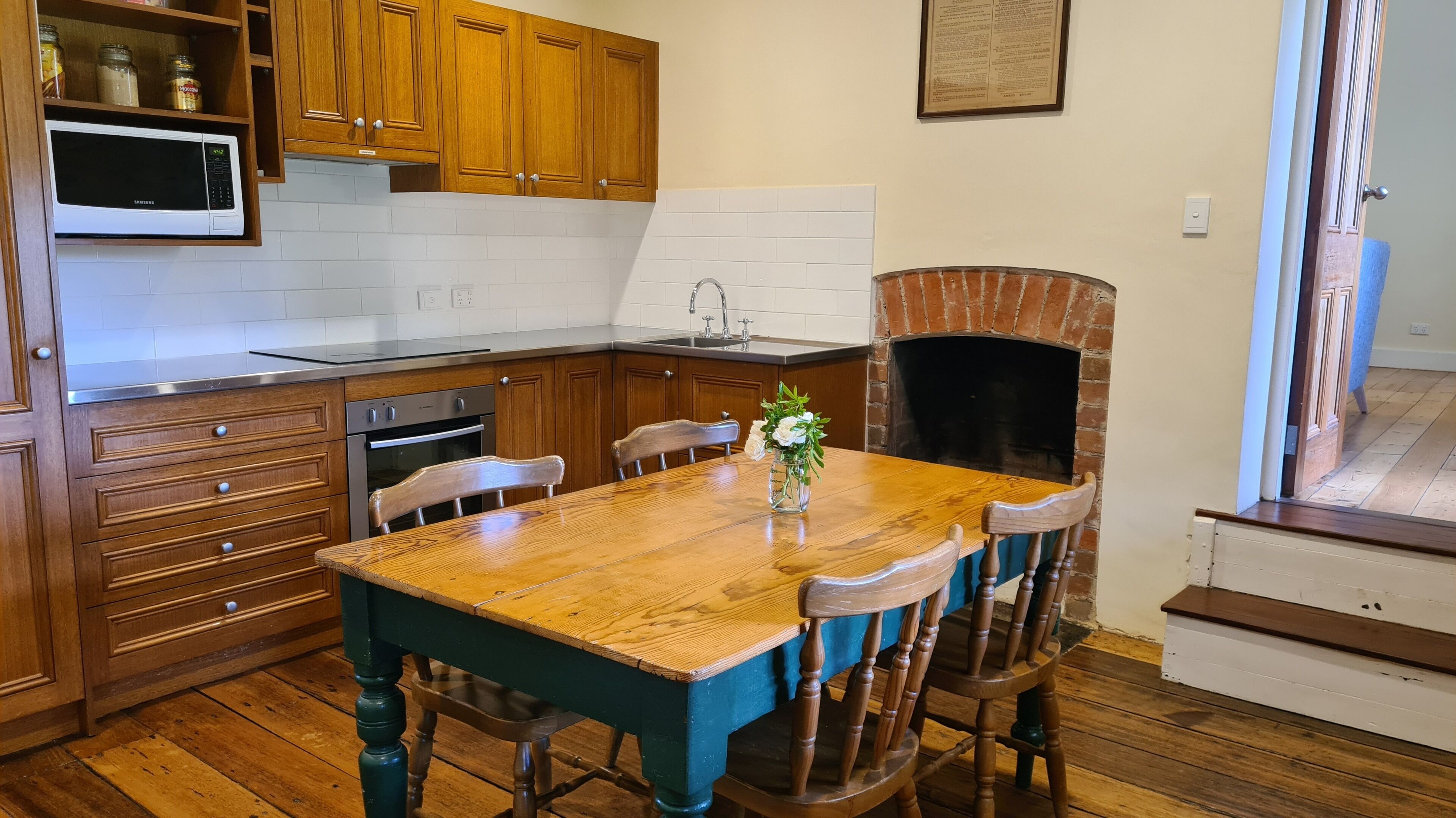 A kitchen with wooden cabinets, a microwave, a sink, and a brick oven.