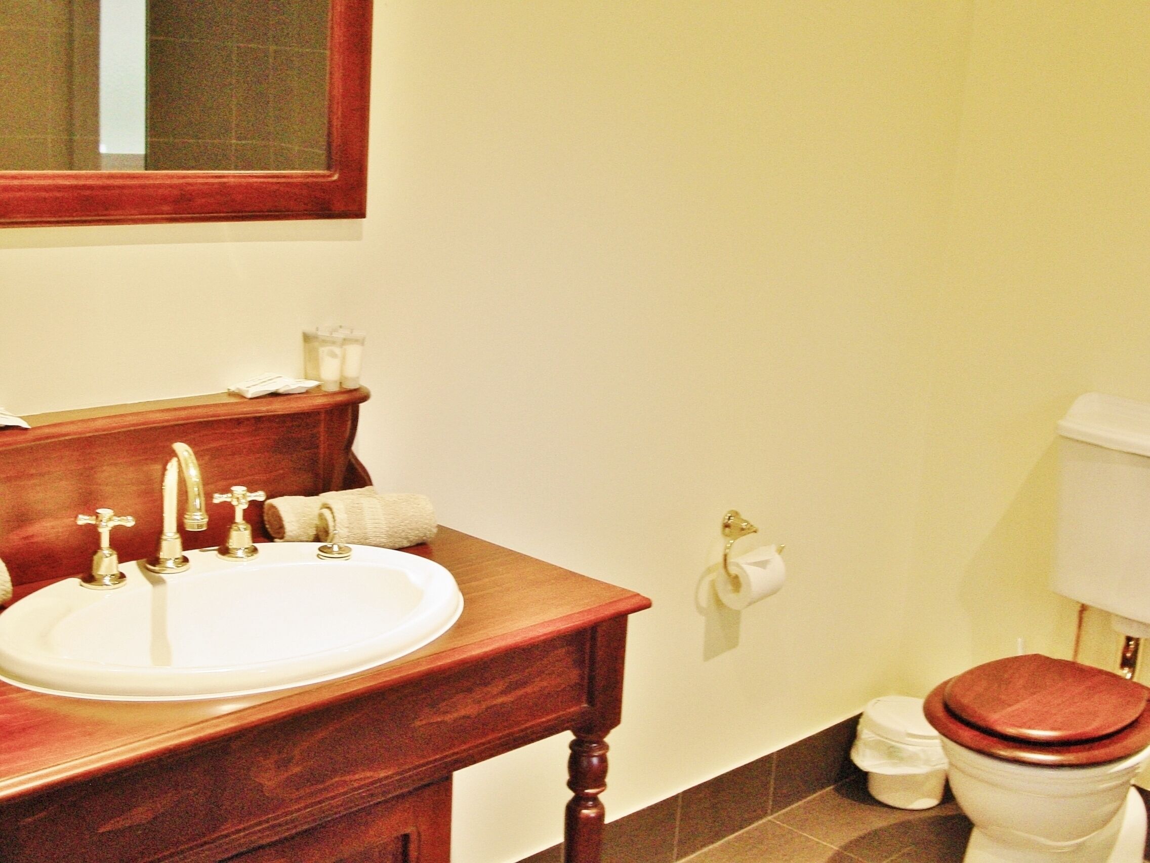 A bathroom with a wooden vanity, a white sink, and a toilet.