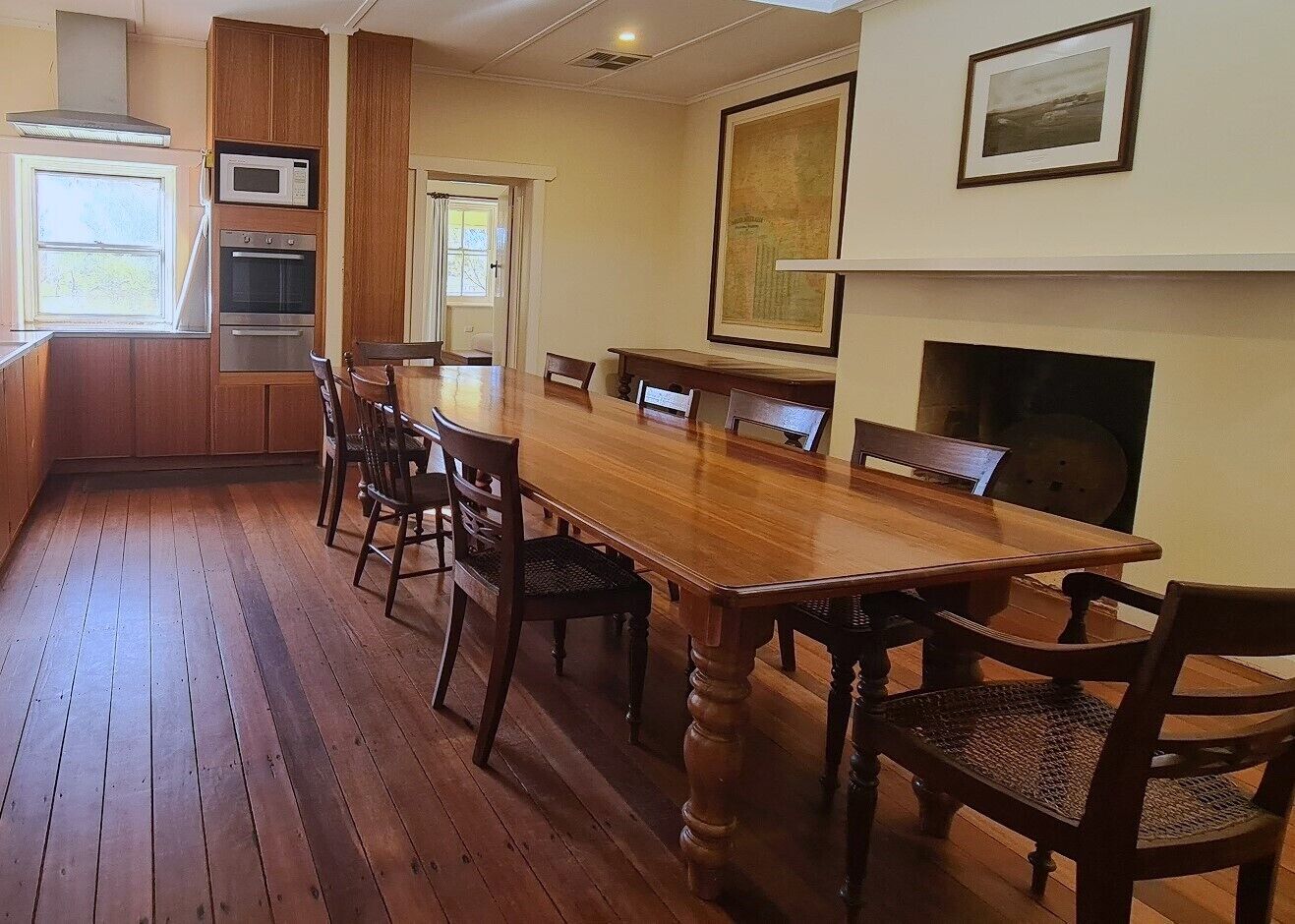 Un comedor amplio con una larga mesa de madera y sillas, un horno empotrado y una chimenea.