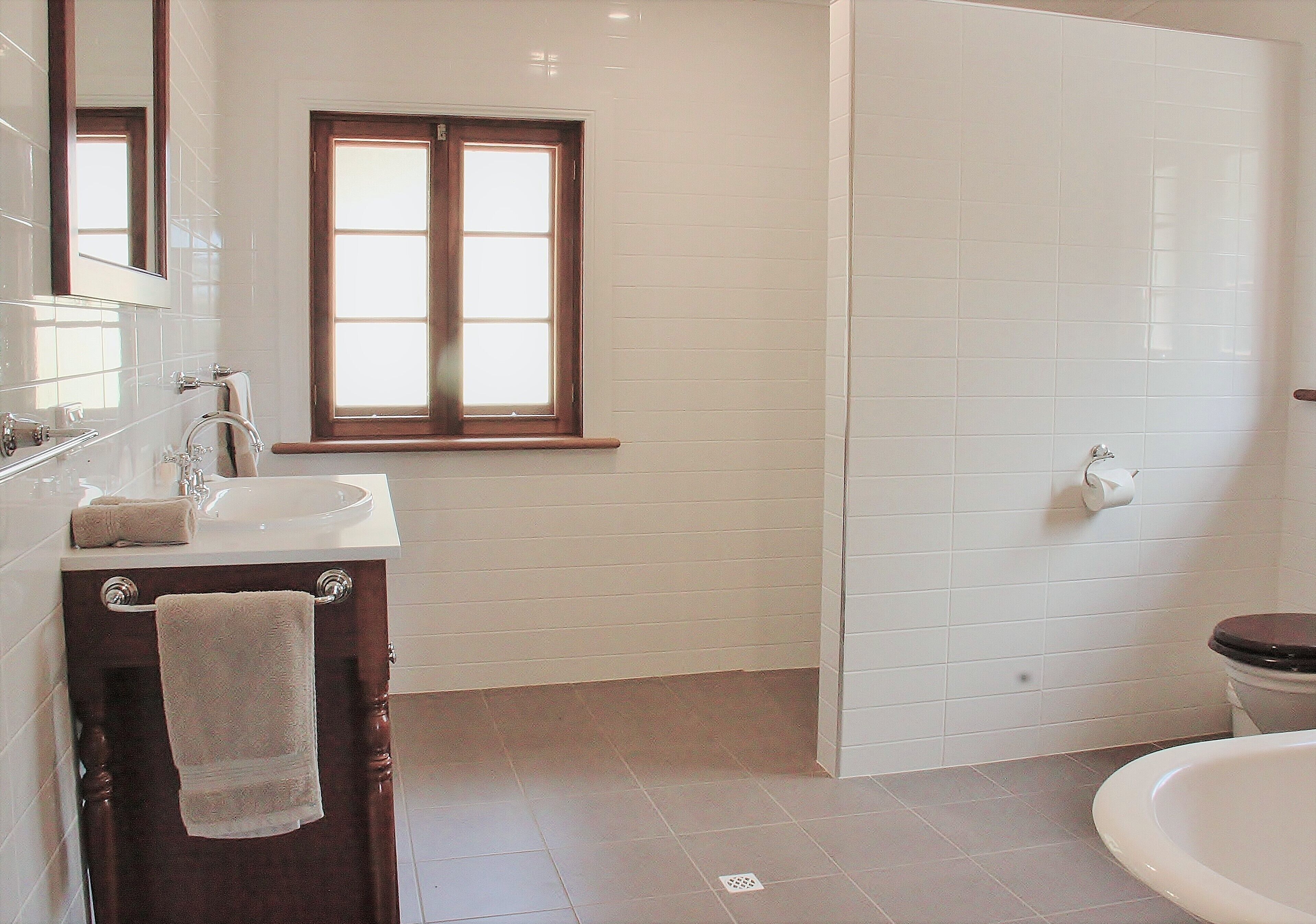 Une salle de bain équipée d’un lavabo, d’un miroir, d’une fenêtre et de toilettes.