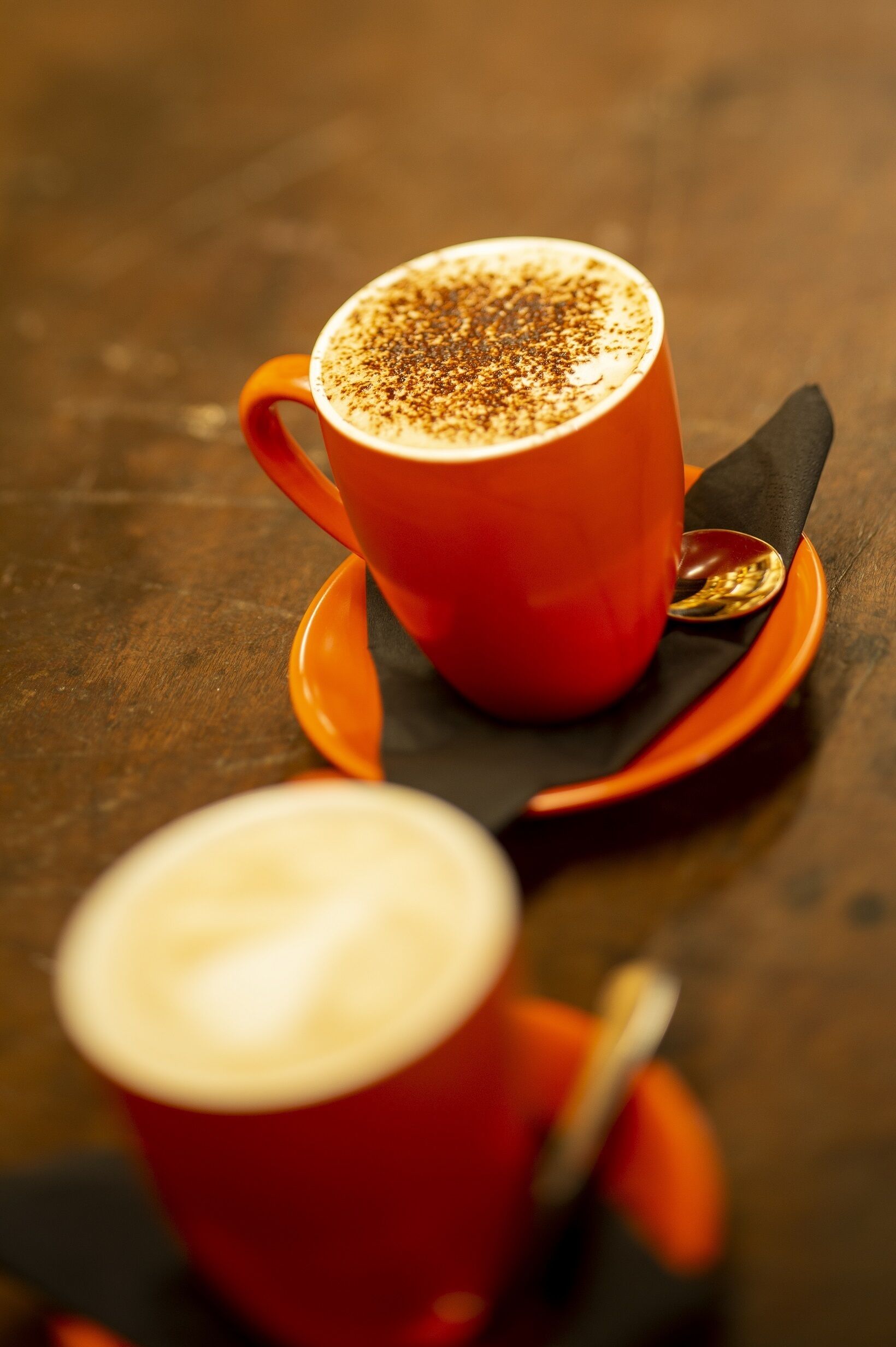Una taza roja con espuma sobre una mesa de madera.